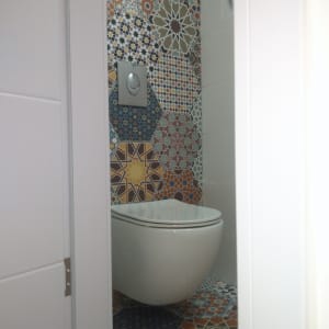 אסלה תלויה עם אריחים מעוצבים צבעוניים על הקיר