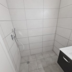 חדר רחצה עם אריחים חדשים ומקלחת מותקנת