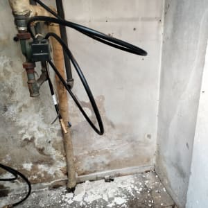 קיר עם צינורות, קילופי צבע ופסולת על הרצפה