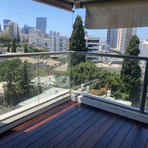 מרפסת עם רצפת עץ ומעקה זכוכית