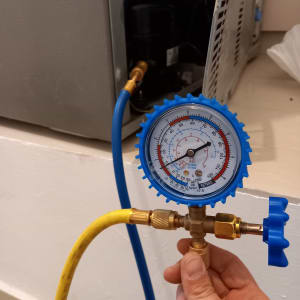 מד לחץ מחובר למקרר עם צינורות כחולים וצהובים