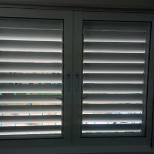 תריסי אלומיניום לבנים בחלון זכוכית כפול