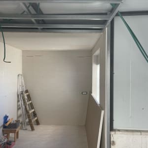 חדר בבנייה עם סולם, לוחות גבס וצינורות ירוקים