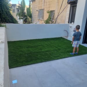 דשא סינתטי ירוק על משטח בטון בחצר קטנה