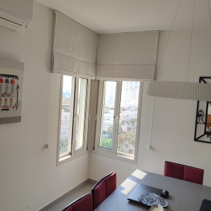 וילון רומי לבן על חלון פינת חדר