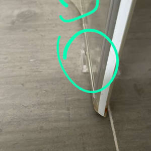 דלת זכוכית למקלחת עם סימני מים על הרצפה