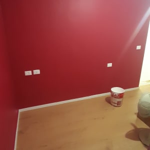 קיר צבוע באדום עם דלי צבע וסולם