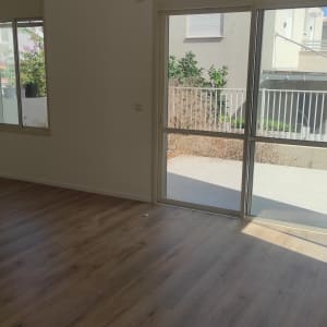 חדר ריק עם רצפת עץ ומטאטא בפינה