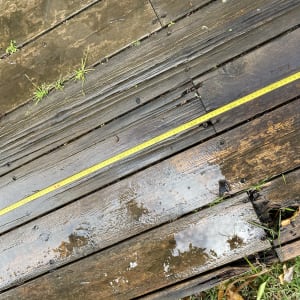 סרט מדידה צהוב על דק עץ רטוב עם עשבים