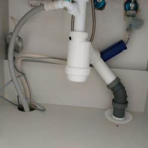 צנרת מתחת לכיור עם מחברים וצינורות פלסטיק