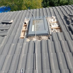 חלון מותקן בגג רעפים אפור עם חבל בטיחות