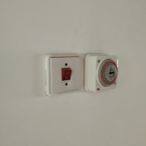 שקע חשמלי עם מתג אדום וטיימר על קיר לבן