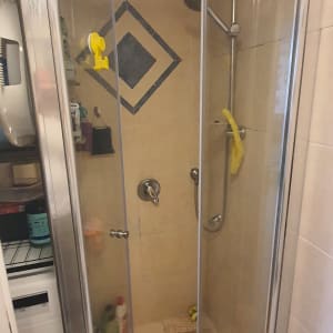 מקלחון עם דלתות זכוכית, ראש מקלחת ומדף מוצרים