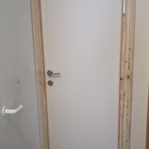 דלת לבנה עם ידית מתכת כסופה ומשקוף עץ