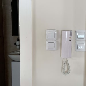 ארבעה מתגי חשמל ואינטרקום על קיר לבן