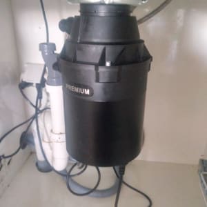 מכשיר טוחן אשפה מתחת לכיור עם צינורות חיבור