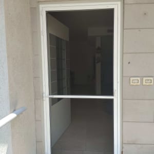דלת אלומיניום עם מסגרת לבנה וזכוכית כהה