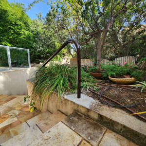 מעקה מתכת שחור ליד מדרגות אבן בגינה