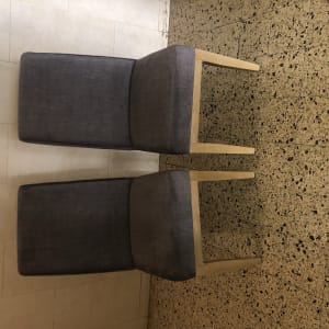 שני כיסאות מרופדים בבד אפור על רצפה מרוצפת