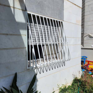 סורגי מתכת לבנים על חלון קיר חיצוני