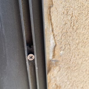 בורג מחובר לתריס מתכת על קיר