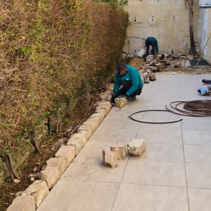 שני אנשים עובדים בגינה, מניחים אבנים לאורך שביל