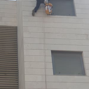 אדם על חבל עם דלי ליד חלון בניין