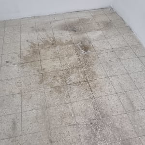 רצפה מלוכלכת עם כתמים כהים שזקוקה לניקוי