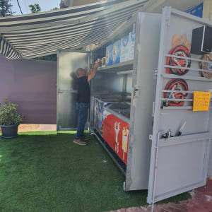 אדם מסדר מוצרים על מדף בתוך דוכן חיצוני