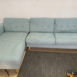 ספה כחולה עם סימני ניקוי וכלי ניקוי על הרצפה