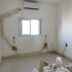 חדר בשיפוץ עם קירות מתוקנים ושקיות חומרי בניין