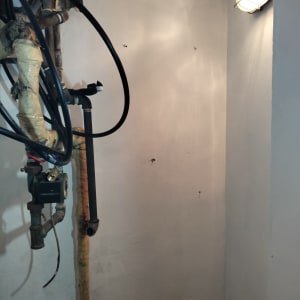 קיר צבוע בלבן עם צינורות וציוד חיווט