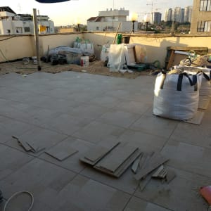 עבודת ריצוף חוץ באריחי גרניט פורצלן במרפסת גג במהלך שיפוץ