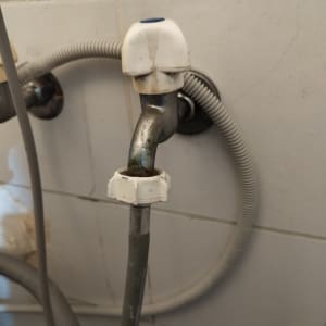 ברז מתכת עם צינור גמיש מחובר לקיר