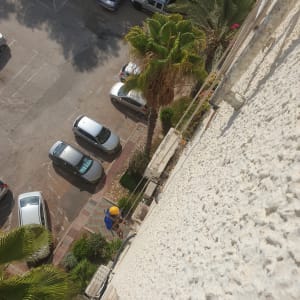 אדם עם קסדה צהובה עובד על קיר בניין