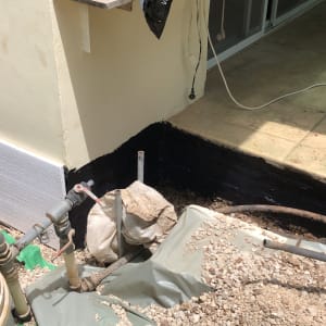 אדם עובד על איטום קיר חיצוני עם חומר שחור