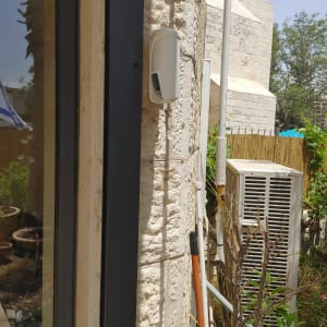 חיישן תנועה מותקן על קיר אבן ליד דלת זכוכית
