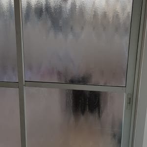 דלת זכוכית חלבית עם מסגרת מתכת לבנה