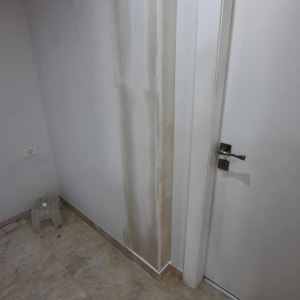 קיר גבס עם סימני רטיבות ליד דלת לבנה