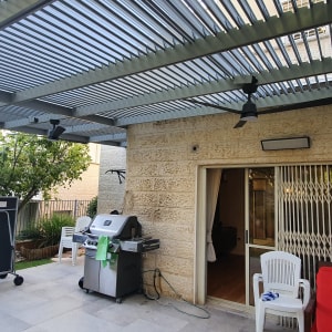 מאווררים ותאורה מותקנים על פרגולה בחצר
