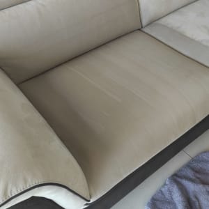 ספה בהירה עם מגבת כחולה על הרצפה