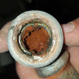 צינור חלוד עם קורוזיה פנימית בידיים של אדם