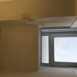 כתם רטיבות על תקרה צבועה ליד חלון