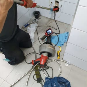 אינסטלטור עובד עם כלי עבודה על צינור קיר