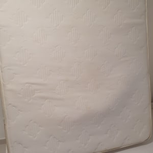 מזרן לבן עם תווית על מסגרת מיטה