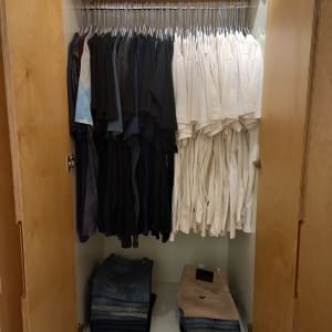 חולצות תלויות ומכנסיים מקופלים בארון עץ