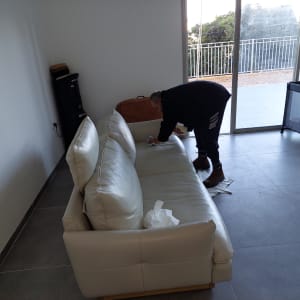 אדם מנקה ספה עם מטלית בחדר מואר