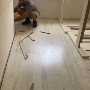 אדם מתקין פרקט עם קרשים שבורים על הרצפה