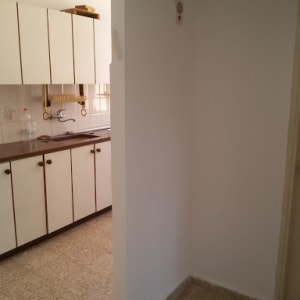 קיר צבוע בלבן ליד מטבח עם ארונות לבנים