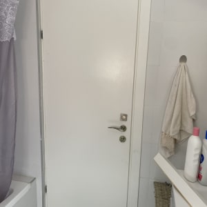 דלת לבנה עם ידית מתכת בחדר אמבטיה
